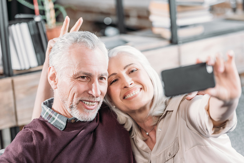 Happy Senior Couple Having Fun While Taking Selfie On Sofa